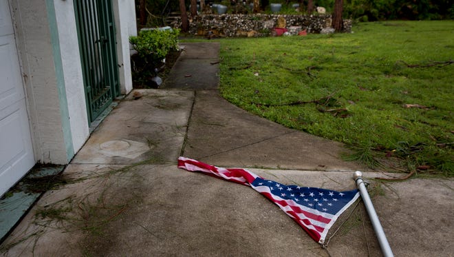 An American flag lays on the ground in the front yard of Rolan Vermette's property a day after Hurricane Irma made landfall in Southwest Florida Monday, September 11, 2017 in East Naples, Fla.