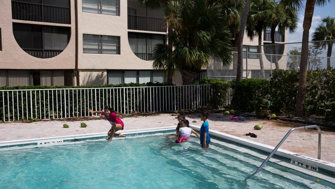 Astrid Santos, 9, jumps into the pool at Angler's Cover Condominiums as her mother Reina Santos, white shirt, and cousins Johanna Leon and Jonathan Leon, 7, look on  Marco Island, Fla. Monday, September 11, 2017.