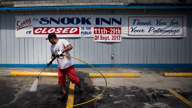 Roberto Valesquez pressure washes the parking lot at the Snook Inn on Marco Island on Tuesday, September 12, 2017, two days after Hurricane Irma.