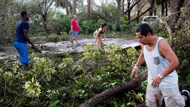 Residents of Windsong Club Apartments clear the main entrance to their complex along Immokalee Road of debris  a day after Hurricane Irma made landfall in Southwest Florida Monday, September 11, 2017 in Naples, Fla.