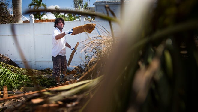 Kristian Schomburg throws debris into a pile while cleaning up at the Snook Inn in Marco Island on Tuesday, September 12, 2017, two days after Hurricane Irma.
