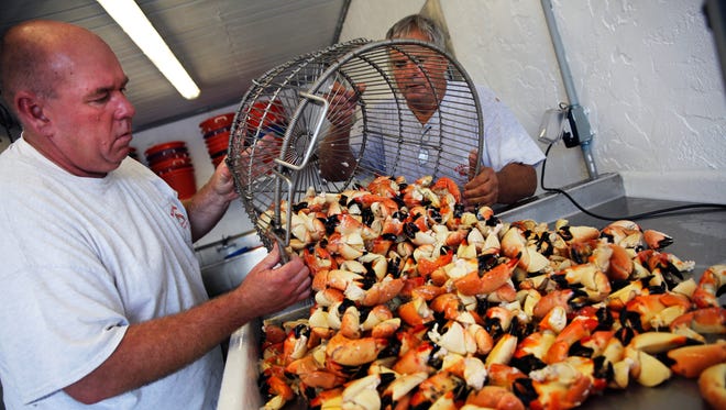 Matt Smith, left, and Damas Kirk dump a basket of freshly cooked stone crab claws for grading on the first day of stone crab seaon at Kirk Fish Company in Goodland on Sunday, Oct. 15, 2017.