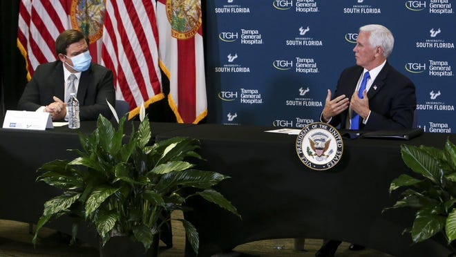 Florida Gov. Ron DeSantis listens to Vice President Mike Pence during a meeting at USF Health's Center for Advanced Medical Learning and Simulation on Thursday in Tampa. The meeting between Pence and DeSantis came on the day Florida registered a record 10,109 new COVID-19 cases.