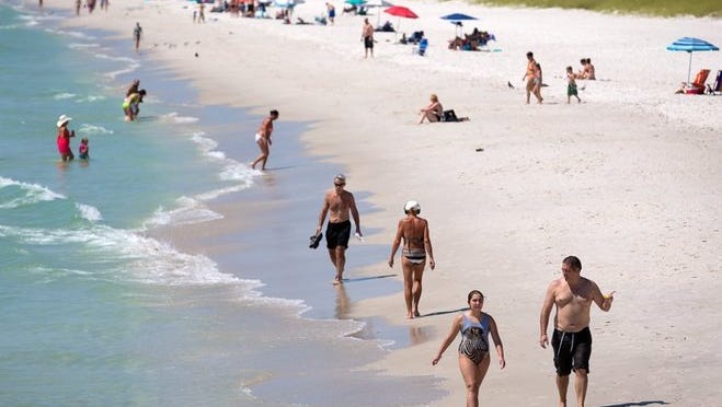 FILE - Beach-goers circulate around the beach near the Naples pier on Tuesday, May 3, 2016, in Naples.