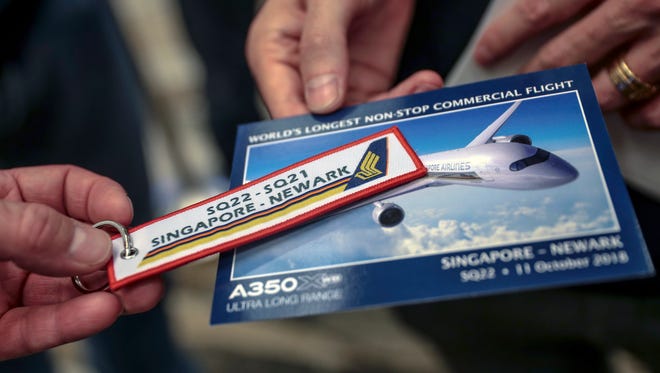 A commemorative keychain and postcard for Singapore Airlines flight SQ22 are seen in Singapore, Oct. 11, 2018. Singapore Airlines (SIA) is restarting its SQ22 flight, a non-stop flight from Singapore Changi Airport to Newark Liberty International Airport.