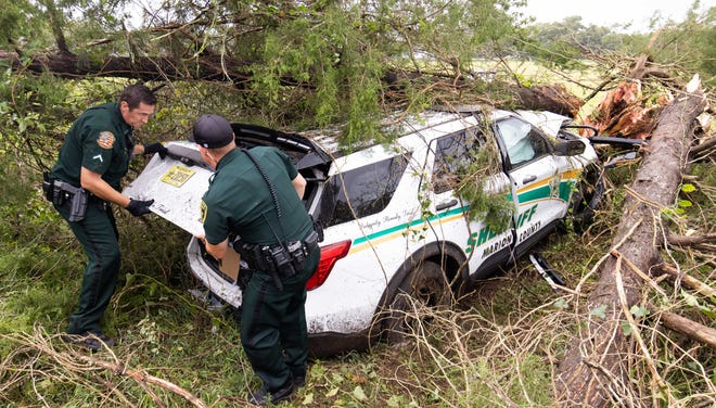 Marion County Deputy Jason Lionnell, left and Deputy Justin Ling, right, grabs Deputy Coleman's personal effects from the wrecked vehicle as Marion County Fire Rescue responded to a single vehicle accident that involved Marion County Sheriff Deputy Jonathan Coleman, Wednesday morning, Aug. 30, 2023 in Ocala, Fla. The deputy was transported from the scene with a possible broken ankle and some cuts an abrasions according to Marion County Chief Deputy Robert Douglas. The accident occurred as Hurricane Idalia passed through Marion County.