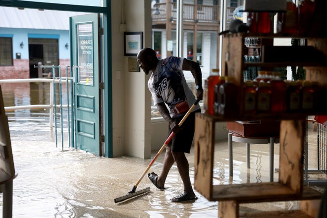 Donnye Franklin helps a friend try to get the flood waters out of his Explorer Manatee Tour store after Hurricane Idalia passed offshore on Aug. 30, 2023 in Crystal River, Fla.