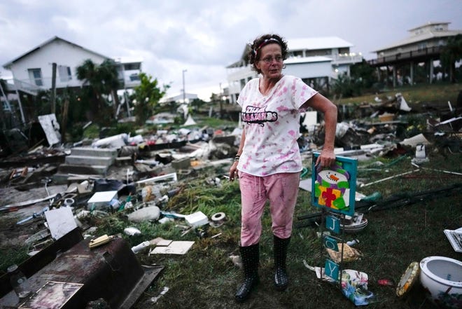 Jewell Baggett stands beside a Christmas decoration she recovered from the wreckage of her mother’s home, as she searches for anything salvageable from the trailer home her grandfather had acquired in 1973 and built multiple additions on to over the decades, in Horseshoe Beach, Fla., after the passage of Hurricane Idalia, Wednesday, Aug. 30, 2023.