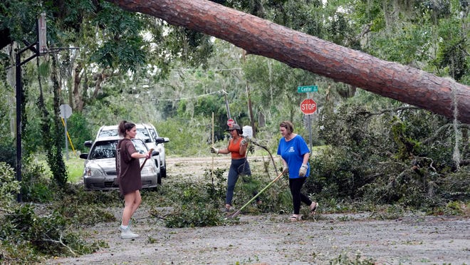 Residents Alana Hall, Kayci Carter, and Tracy Hall clean up debris caused by Hurricane Idalia in front of their home Wednesday, Aug. 30, 2023, in Perry, Fla.