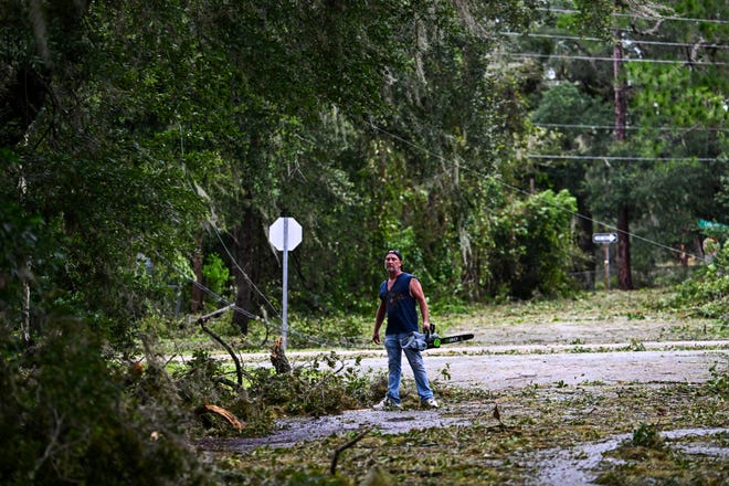 Matt Devens clear trees from his front yard in Perry, Fla. on Aug. 30, 2023 after Hurricane Idalia made landfall.