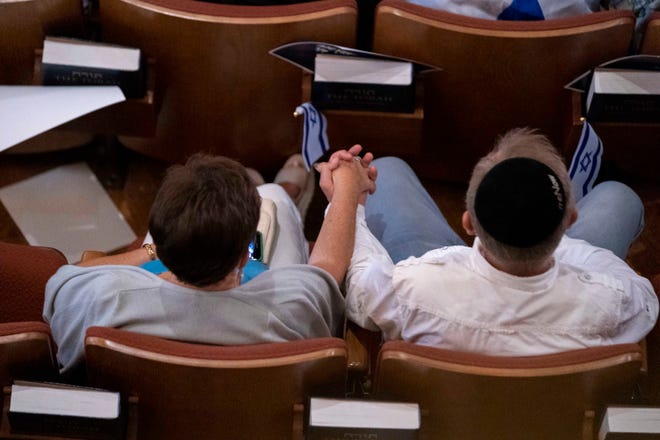 People hold hands during an event to show solidarity for Israel at Congregation B'Nai Israel in Boca Raton, Florida on October 10, 2023.