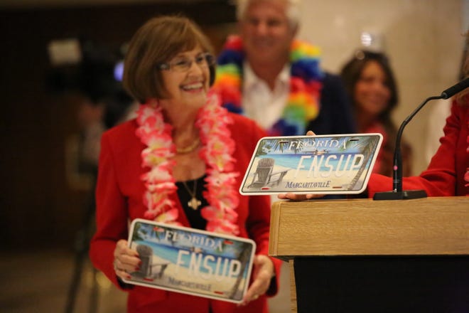 Sen. Gayle Harrel, R- Jupiter, smiles and holds the Jimmy Buffett specialty license plate prototype inside the Florida Capitol, Jan. 25, 2024.
