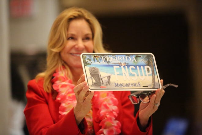 Rep. Linda Chaney, R- St. Petersburg, holds up a Jimmy Buffett specialty license plate prototype, Jan. 25, 2024.
