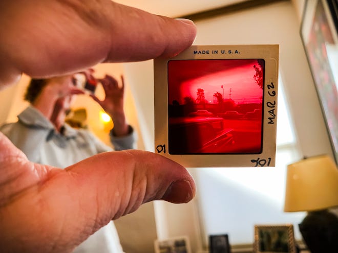 While on a trip home to San Jose, California in 2020, Andrew Dolph, a staff photographer at the Times-Reporter, views a 3 1/4 inch slide depicting a solar eclipse that likely occurred in February of 1962. The photograph was made by his grandfather, Carroll Sears Rankin, while standing in the driveway of their home in Palo Alto, California. Pictured at left is Andrew's mother, Gratia Rankin.