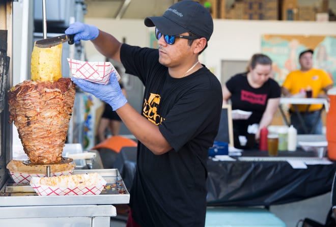 Jay Torres slices pineapple to top off a taco dish prepared for a customer while serving at Momentum Brewery on July 25, 2018. Neiva and Alan Romero opened El Local food truck in April 2017. The truck started having mechanical issues after Hurricane Irma. Since then, theyÕve been serving their authentic Mexican dishes out of a mobile food stand.