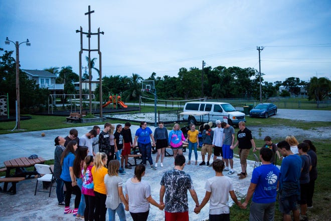 Members of the youth group hold hands in a prayer circle during their outdoor service at Chokoloskee Church of God in Chokoloskee on Wednesday, Aug. 29, 2018. Although damage to the church's main building from Hurricane Irma was restored in December, they are still raising funds to rebuild the teen center, which was previously located on the concrete slab seen beneath them.