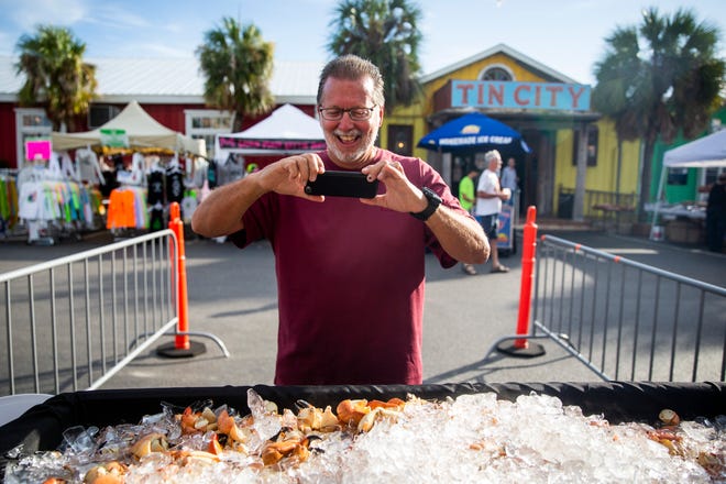 Tom Foos of Cleveland, Ohio, takes a photo of stone crab claws during the fist day of the Naples Stone Crab Festival on Friday, October 26, 2018, at Tin City Shops in Naples. Foos, who travels to Naples for the festival with his wife every year, took the photo to send to friends and family in Ohio. "They're gonna be so mad," he said.