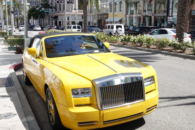 A big yellow Rolls Royce is parked on Rodeo Drive - and has a ticket for parking too long.