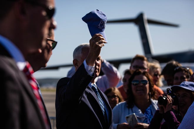 Vice President Mike Pence holds up a cap before autographing it at the Naples Airport on Thursday, March 28, 2019.