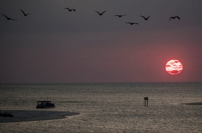 A sunset cruise enjoys the ball of fire before it sets on the horizon at New Pass on the south end of Lovers Key in Bonita Springs on Wednesday April, 3, 2019.