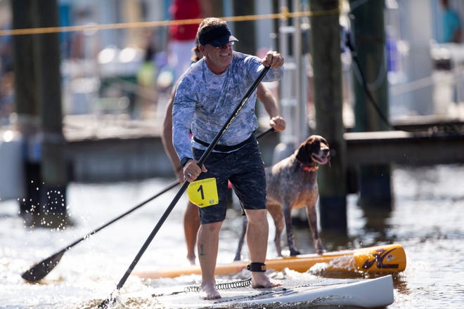 Joe Setaro of Cape Coral takes the lead over Naples resident, Iggy Sprude and his dog Charlie in the amateur stand up paddleboard race, Saturday, May 11, 2019, at the 43rd annual Great Dock Canoe Race at Crayton Cove in Naples.