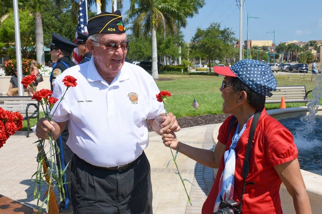 Terry Tobin of the American Legion gives a carnation to Maria Lamb. Marco Island commemorated Memorial Day on Monday morning with a ceremony at Veterans' CommunityPark, with a keynote address by American Legion Post #404 Commander Lee Rubenstein.