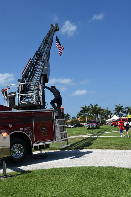 Firefighter Steve Harvey positions a flag on the department's tower truck. Marco Island commemorated Memorial Day on Monday morning with a ceremony at Veterans' CommunityPark, with a keynote address by American Legion Post #404 Commander Lee Rubenstein.