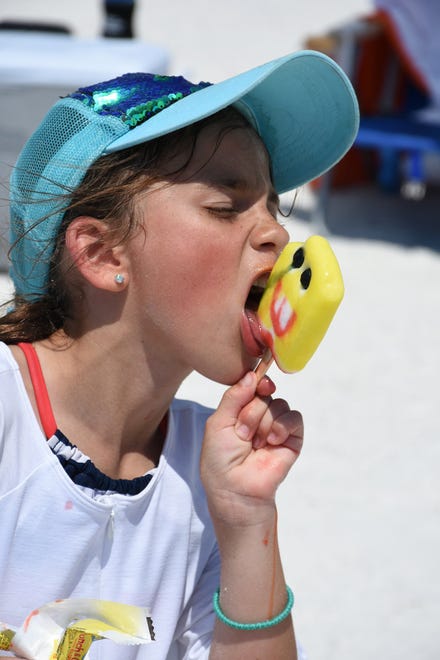 Kate Osenga, 7, works on her SpongeBob popsicle. Marco Island's Fourth of July was a day at the beach, with activities, splashing and thousands thronging the shore for Uncle Sam's Sand Jam.