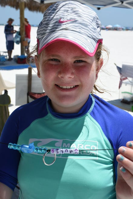 Julia Stamolis, 10, makes an I.D. bracelet for herself. Marco Island's Fourth of July was a day at the beach, with activities, splashing and thousands thronging the shore for Uncle Sam's Sand Jam.