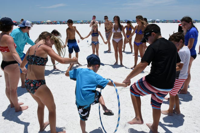 Kids compete in wriggling through a hula hoop. Marco Island's Fourth of July was a day at the beach, with activities, splashing and thousands thronging the shore for Uncle Sam's Sand Jam.