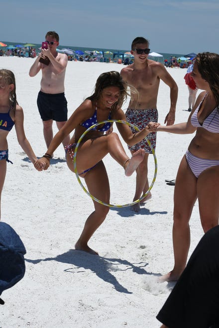 Kids compete in wriggling through a hula hoop. Marco Island's Fourth of July was a day at the beach, with activities, splashing and thousands thronging the shore for Uncle Sam's Sand Jam.