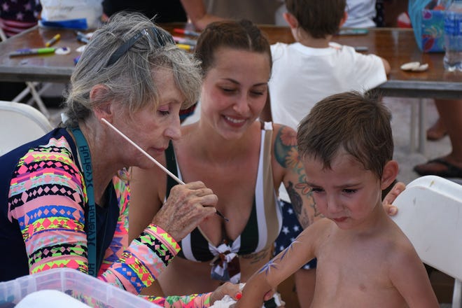 Lola Dial of the city's Parks & Rec, Dept. paints faces, and also arms, working on Waylon Dowdy, 3, during the Sand Jam. Marco Island's Fourth of July was a day at the beach, with activities, splashing and thousands thronging the shore for Uncle Sam's Sand Jam.