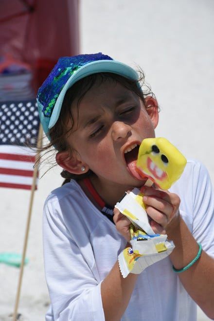 Kate Osenga, 7, works on her SpongeBob popsicle. Marco Island's Fourth of July was a day at the beach, with activities, splashing and thousands thronging the shore for Uncle Sam's Sand Jam.