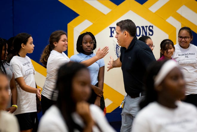 Chris Gelardi high-fives students before they begin their fitness test during a physical education class at Golden Gate Middle School on Thursday, Aug. 22, 2019.