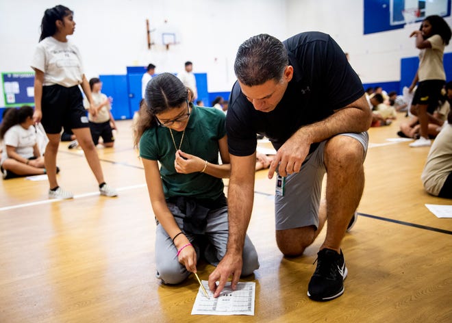 Chris Gelardi helps Emily Virula Ayala fill out a paper during a physical education class at Golden Gate Middle School on Thursday, Aug. 22, 2019.