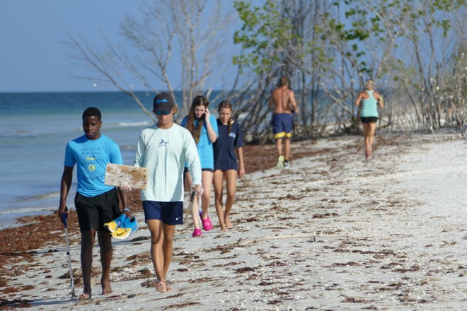 Landon McLain, right, from Marco Island Academy carries a piece of wood, attached nails included, during the International Coastal Cleanup in Tigertail Beach in 2019.