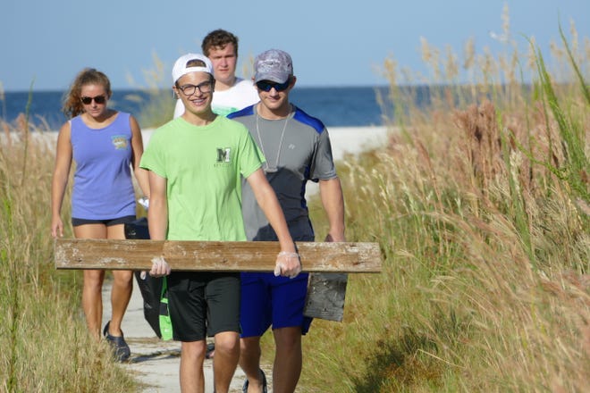 Teens carry pieces of wood during the International Coastal Cleanup in Tigertail Beach in Marco Island on Sept. 21, 2019.