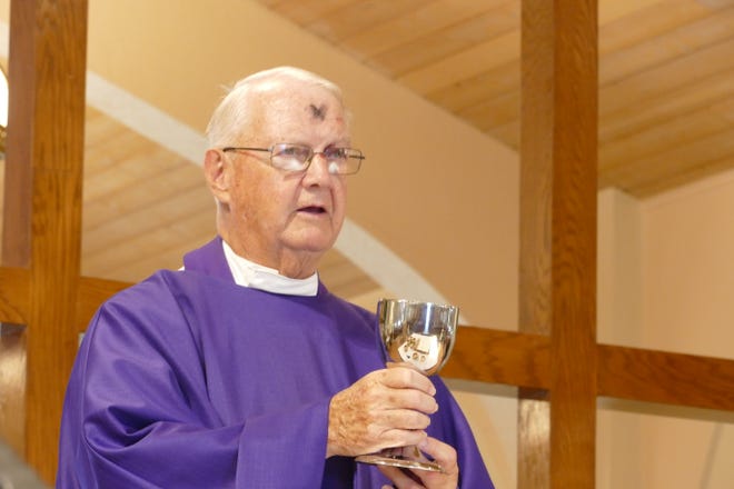 Father Jack O'Leary holds a chalice during an Ash Wednesday service at San Marco Catholic Church on Feb. 26, 2020.