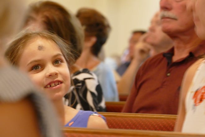 A girl smiles during an Ash Wednesday service at San Marco Catholic Church on Feb. 26, 2020.