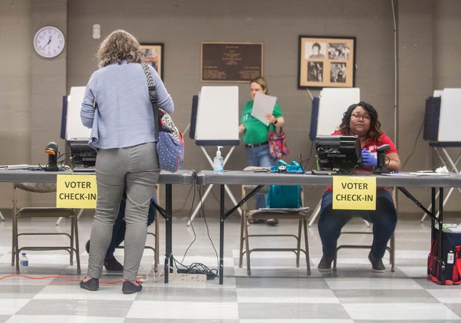 Poll workers wear gloves and have bottles of hand sanitizer ready for voters as they cast their ballot in the Florida primary election, Tuesday, March 17, 2020.