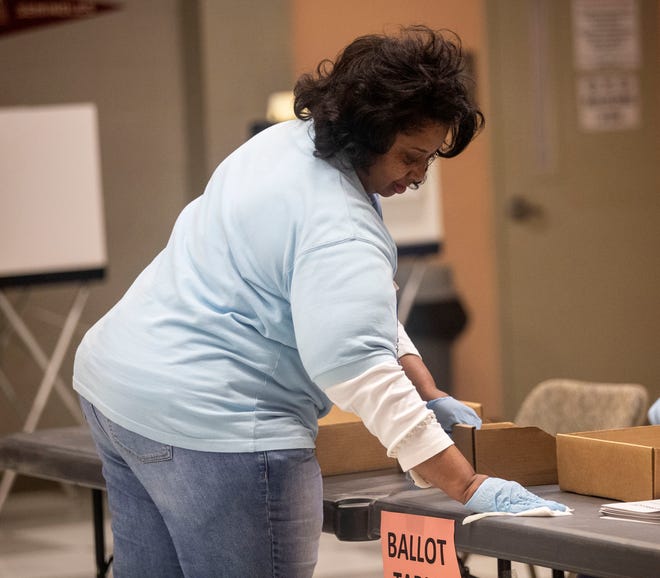 A poll worker wipes down a table at the precinct, Tuesday, March 17, 2020.