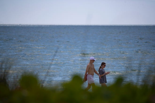 Community members and tourist take a stroll along the shore in Naples on Friday, March 20, 2020,.