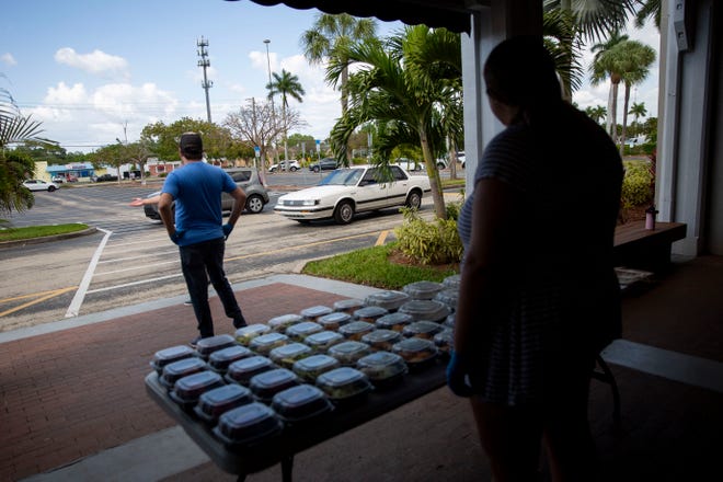 Volunteers wait for people to drive up to get meals at Broadway Palm Dinner Theatre in Fort Myers on Saturday, March 21, 2020.
