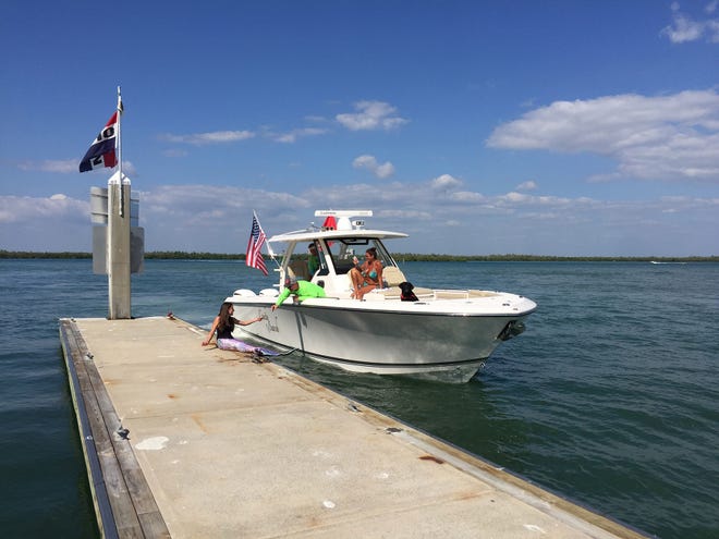 Dr. Rick Siegel aboard "Cavity Search" donates a $20 tip to the little mermaid. Summer Joy Hill, 16, has been donning her mermaid tail and waving to passing boats to cheer people up during the coronavirus pandemic.