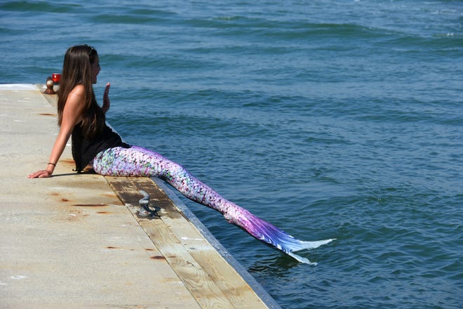 Summer waves to a passing boatload of kids. Summer Joy Hill, 16, has been donning her mermaid tail and waving to passing boats to cheer people up during the coronavirus pandemic.