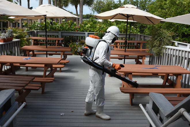 Technician Owen Maynard disinfects the seating area at the Tigertail Beach Cafe. HydroClean Environmental Solutions is a startup dedicated to disinfecting local businesses to enhance customer safety.