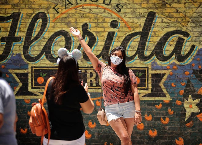 Guests take pictures at Disney Springs in Orlando, Florida, on May 20, 2020. Walt Disney World's sprawling shopping and dining complex is beginning the first phase of getting back to business with 44 establishments welcoming the public amid the coronavirus pandemic.
