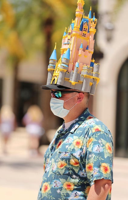 A guest wears a distinctive castle hat that appears to modeled after Disney World's Cinderella Castle at Disney Springs in Orlando on May 20, 2020.
