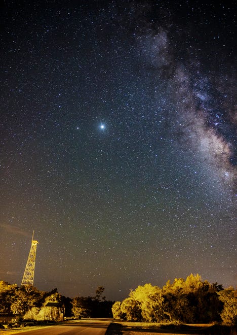 The milky way looms over the old fire tower at Fakahatchee Strand Preserve State Park in Copeland, Florida in the early morning hours of June 17, 2020. Photographed with a Canon 1DX Mark II at 30 sec. with a 24-70mm lens set at 24mm at ISO 1600 set at 2.8 aperture. The milky way can best be photographed and viewed on moonless nights away from light pollution. In Florida the best time to view the milky way is April-September. It will be visible in the southern sky.