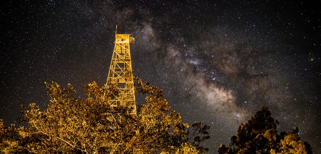 The milky way looms over the old fire tower at Fakahatchee Strand Preserve State Park in Copeland, Florida in the early morning hours of June 17, 2020. Photographed with a Canon 1DX Mark II at 30 sec. with a 24-70mm lens set at 24mm at ISO 1600 set at 2.8 aperture. The milky way can best be photographed and viewed on moonless nights away from light pollution. In Florida the best time to view the milky way is April-September. It will be visible in the southern sky.